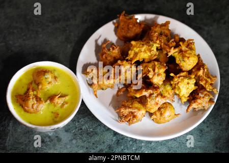 Gros plan de Kadhi Pakoda ou pakora et oignon frit conservés dans une assiette et un bol en céramique blanche, Bhaji kanda croustillant, cuisine indienne, Pune, Maharashtra, Inde Banque D'Images