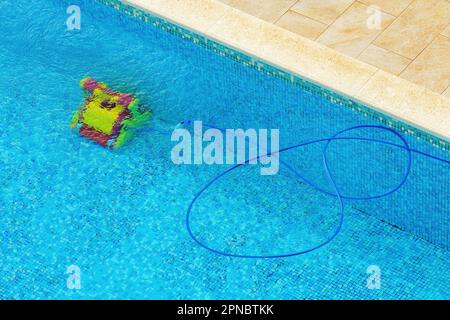 Nettoyeur de piscine robotique en opération au fond de la piscine, vue en grand angle Banque D'Images