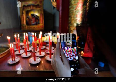 La pagode ONG bon (temple Nhi Phu) est la plus ancienne pagode chinoise de Saigon. Chandeliers rouges. Offrandes lors d'une cérémonie. Femme qui fait de la vidéo avec un smartphone Banque D'Images