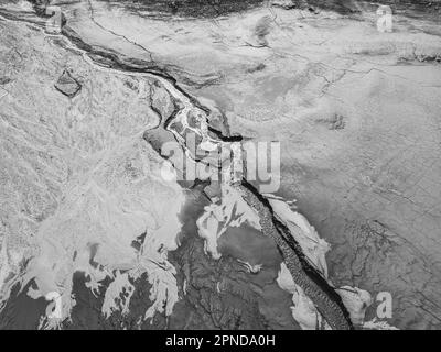 La structure de la terre mouillée fissurée au fond du lac, créant des patrons, structure, arrière-plan irréguliers. Des formes étonnantes créées par la nature à Banque D'Images