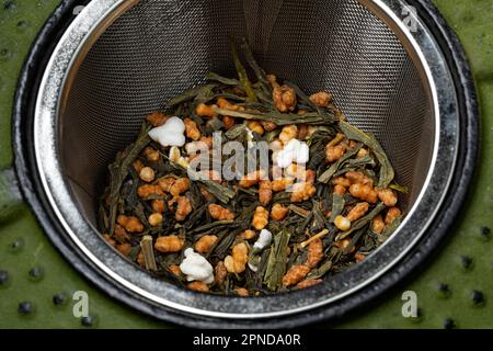 Genmaicha, thé japonais dans un infuser de thé d'une théière en fonte gros plan Banque D'Images