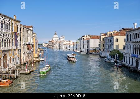 Venise, Italie : Panorama du Grand Canal de Venise avec des bateaux et église Santa Maria della Salute au coucher du soleil depuis le pont Ponte dell'Accademia. Banque D'Images