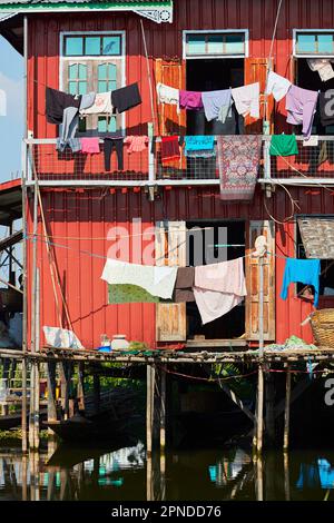 Une maison palafitte colorée sur pilotis (habitations en tas ou habitations lacustres) avec des vêtements suspendus à sécher sur le lac Inle, État de Shan, Myanmar. Banque D'Images