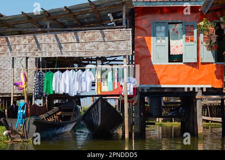 Une maison palafitte colorée sur pilotis (habitations en tas ou habitations lacustres) avec des vêtements suspendus à sécher sur le lac Inle, État de Shan, Myanmar. Banque D'Images