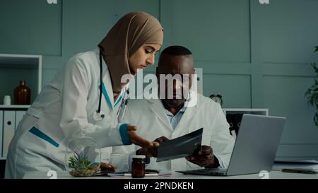 Les collègues des médecins multiraciaux discutent du travail d'équipe d'un homme africain et d'une femme arabe deux professionnels de la santé parlent de l'IRM de contrôle de santé Banque D'Images