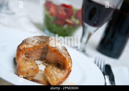 Steak de saumon et salade servis avec du vin rouge Banque D'Images