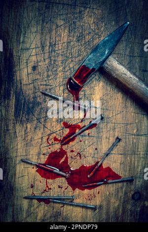 marteau et ongles sanglants sur fond en bois Banque D'Images