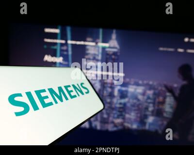 Téléphone mobile avec logo du conglomérat allemand Siemens AG sur écran devant le site Web des affaires. Mise au point au centre-gauche de l'écran du téléphone. Banque D'Images