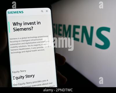 Personne tenant smartphone avec la page web du conglomérat allemand Siemens AG sur l'écran devant le logo d'entreprise. Concentrez-vous sur le centre de l'écran du téléphone. Banque D'Images