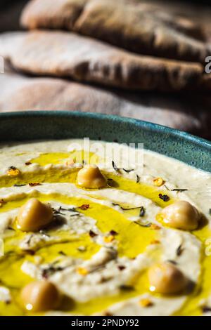 Houmous faits maison recouverts de pois chiches et d'huile d'olive. Ci-dessus, gros plan. Banque D'Images