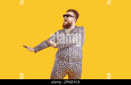 Homme drôle et de taille plus dans des lunettes de soleil et le léopard PJs danse et chant dans le studio de mode Banque D'Images