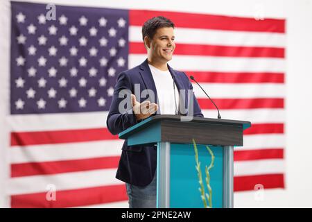 Orateur masculin donnant un discours sur un piédestal avec le drapeau des États-Unis en arrière-plan Banque D'Images