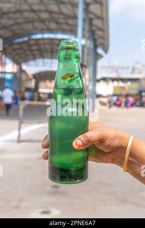 Une jeune femme tenant une bouteille de soda de goli un beau jour. bouteille de soda avec bouchon circulaire en marbre. Une boisson traditionnelle rafraîchissante Banque D'Images