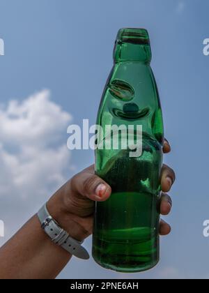 Une jeune femme tenant une bouteille de soda de goli un beau jour. bouteille de soda avec bouchon circulaire en marbre. Une boisson traditionnelle rafraîchissante Banque D'Images