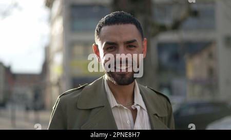 Un jeune homme du Moyen-Orient debout dans la rue de la ville souriant à la caméra. Suivi tourné en mouvement d'un homme arabe marocain avec une expression joyeuse Banque D'Images