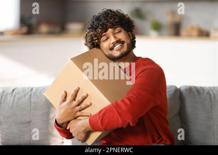 Portrait de Happy Indian Man embrassant boîte en carton avec livraison à la maison Banque D'Images