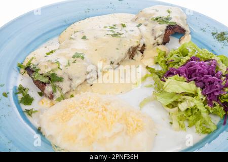 Délicieux steak grillé accompagné de sauce au fromage, servi avec une salade et une purée de pommes de terre. Banque D'Images