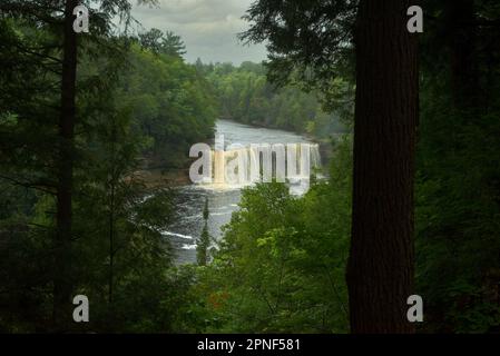 Les chutes supérieures du parc national de Tahquamenon Falls, dans la péninsule supérieure du Michigan, sont visibles à travers les arbres par une journée de mauvaise humeur Banque D'Images