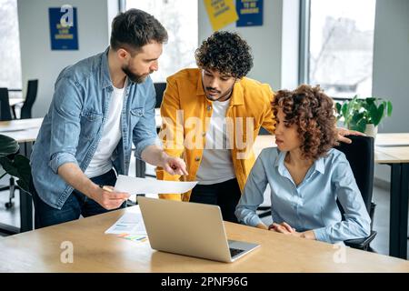 Concept de collaboration. Personnes réussies de différentes nationalités, équipe d'affaires créative, travaillant ensemble sur un projet dans un bureau moderne, regardant la présentation, discutant des idées, brainstorming Banque D'Images