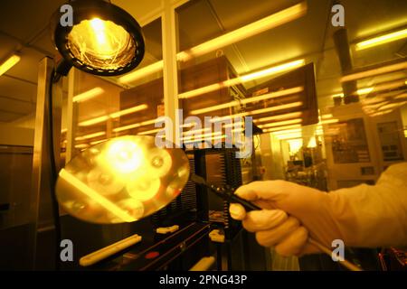 Itzehoe, Allemagne. 04th avril 2023. Un employé de la production de plaquettes travaille sous la lumière jaune dans la salle blanche de la société de semi-conducteurs Vishay Siliconix Itzehoe GmbH. Les plaquettes sont des plaquettes de silicium qui servent de supports pour la production de micropuces. Credit: Christian Charisius/dpa/Alay Live News Banque D'Images