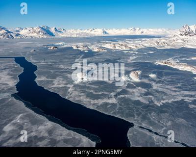 Vue aérienne, paysage d'hiver, vue d'en haut à la mer partiellement gelée, montagnes en arrière-plan, Kulusuk, Groenland oriental, Groenland Banque D'Images