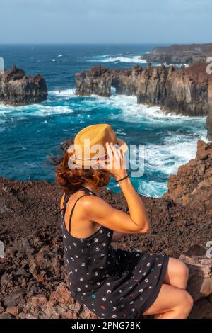 Île El Hierro. Îles Canaries, un jeune touriste dans l'Arco de la Tosca assis. monument sur la côte Banque D'Images