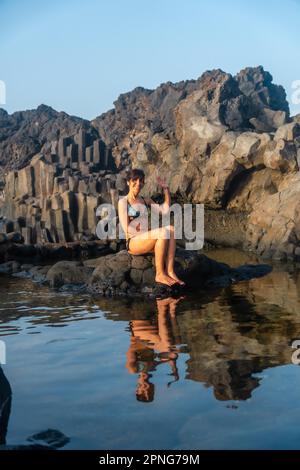 Coucher de soleil sur l'île El Hierro. Îles Canaries, une touriste se baignant dans la piscine naturelle de Charco Azul Banque D'Images