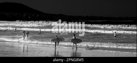 Photographie en noir et blanc, surfeurs sur la plage, Playa Famara, Lanzarote, Iles Canaries, Espagne Banque D'Images