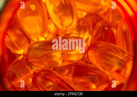 beaucoup de capsules de gélatine jaune sur fond rouge. vitamines omega, gros plan, macro. Banque D'Images