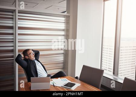 Se sentir détendu par rapport à son succès. Photo en grand angle d'un homme d'affaires charmant assis avec ses mains derrière sa tête dans son bureau d'entreprise. Banque D'Images