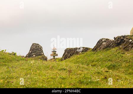 Vestmannaeyjar, Islande- août 2021 : petit phare noir dans une vallée verdoyante de l'île de Vestmannaeyjar, en Islande, Banque D'Images