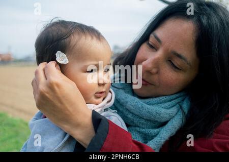 gros plan de la mère souriante et de la petite fille qui ramasse des fleurs de cerisier pendant la saison des fleurs au printemps. concept de la maternité et de profiter du temps togeth Banque D'Images