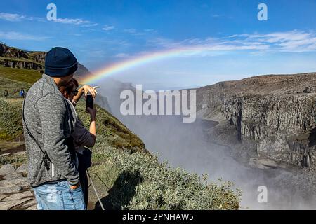 Dettifoss, Islande - août 2021 : les touristes prennent des photos dans un arc-en-ciel unique et rare au-dessus de la cascade de Dettifoss, avec des eaux massives de pulvérisation et de stea Banque D'Images