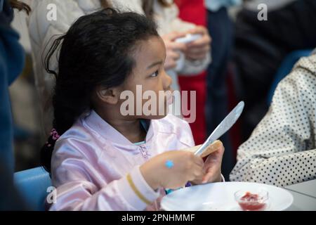 Eat, Allemagne. 19th avril 2023. Une écolière distribue du pain avec de la confiture, le projet Brotzeit est destiné à permettre aux enfants de commencer la journée d'école avec le petit déjeuner, l'actrice Uschi GLAS, présidente du projet brotzeit, visite l'école Bischof von Ketteler d'Essen, 19 avril 2023 Credit: dpa/Alamy Live News Banque D'Images