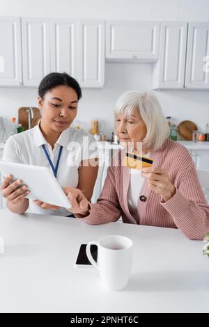 brunette travailleur social multiracial enseignant à la femme sénior comment faire des achats en ligne Banque D'Images