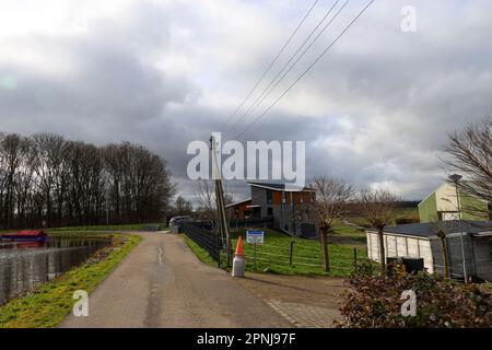 Canal circulaire du Zuidplaspolder avec des nuages sombres au-dessus de lui à Moordrecht aux pays-Bas avec des poteaux électriques en bois Banque D'Images