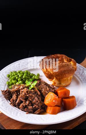 Concept alimentaire bœuf râpé braisé à la bière maison avec pudding du yorkshire sur fond noir avec espace de copie Banque D'Images