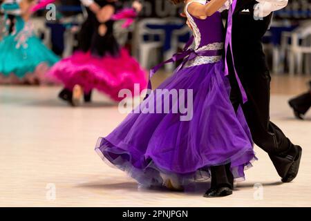 jeunes couples danseurs valse dansant en dancesport compétition, robes colorées pour filles et queue noire pour garçons Banque D'Images