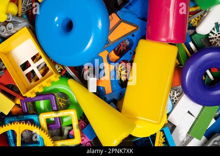 Une abondance de jouets dans la chambre des enfants, beaucoup de pièces en plastique multicolores de designers, pièces de rechange pour jouets, figurines et cubes. Banque D'Images