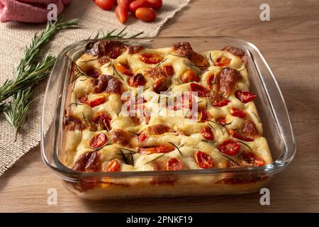 Focaccia italien de Pugliese maison avec romarin et huile sur bois rustique. Banque D'Images