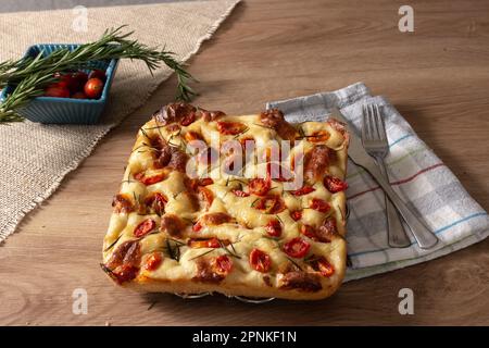 Focaccia italien de Pugliese maison avec romarin et huile sur bois rustique. Banque D'Images