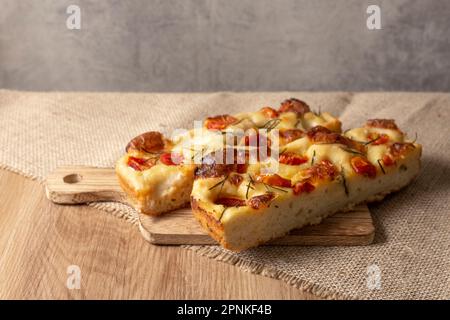 Focaccia italien de Pugliese maison avec romarin et huile sur bois rustique. Banque D'Images