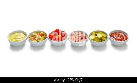 Rangée de bols à légumes avec concombres, ketchup, tomates, moutarde, chou-fleur, chou Banque D'Images