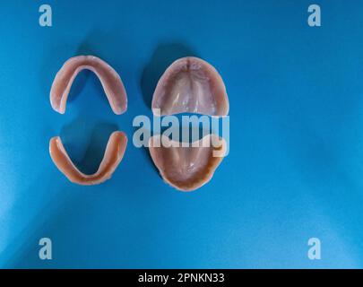 Deux paires de dentiers (haut et bas) - fausses dents amovibles en acrylique isolé sur fond bleu - les deux ensembles sont orientés vers le bas Banque D'Images