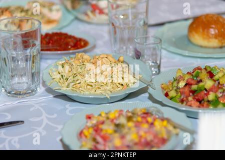 Différentes salades sur des assiettes blanches restant sur la table de banquet. Chou en tranches, maïs, tomate, poivre, concombre, plats végétariens sains. Mise au point sélective. Photo de haute qualité Banque D'Images