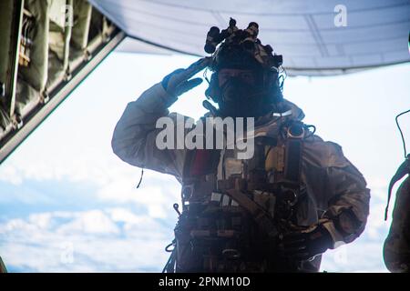 Une Béret verte avec 10th membres du Groupe des forces spéciales (aéroporté) salue avant de se préparer à sauter d'un Boeing C-130 lors d'une opération militaire de chute libre conjointe avec les forces spéciales canadiennes, tout en participant à la rotation 23-2 du joint Pacific multinational Readiness Centre, en Alaska, le 31 mars 2023. L'Alaska offre un environnement arctique optimal aux opérateurs et aux forces partenaires pour former et mettre en œuvre des tactiques qu'ils peuvent être prêts à exécuter au cours de futures missions. L'exécution des opérations de chute libre permet à des opérations spéciales de fournir du personnel, de l'équipement et des fournitures à partir d'un Banque D'Images