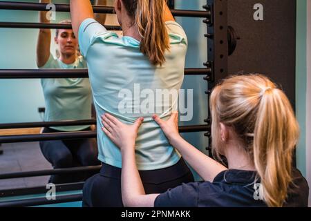 Jeune femme à la séance de physiothérapie être aidé avec des douleurs et des exercices dans le bas du dos Banque D'Images