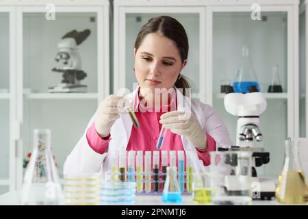 Un jeune technicien de laboratoire examine les tubes à essai avec des liquides Banque D'Images