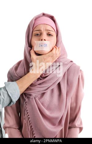 Femme musulmane à la bouche et main de son mari sur fond blanc. Concept de violence domestique Banque D'Images