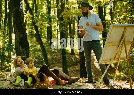 Capturez l'instant. Beauté de la nature. Homme barbu femme et fils relax l'automne nature. Tirer de la vie. Peintre avec famille se détendre en forêt. Art Banque D'Images